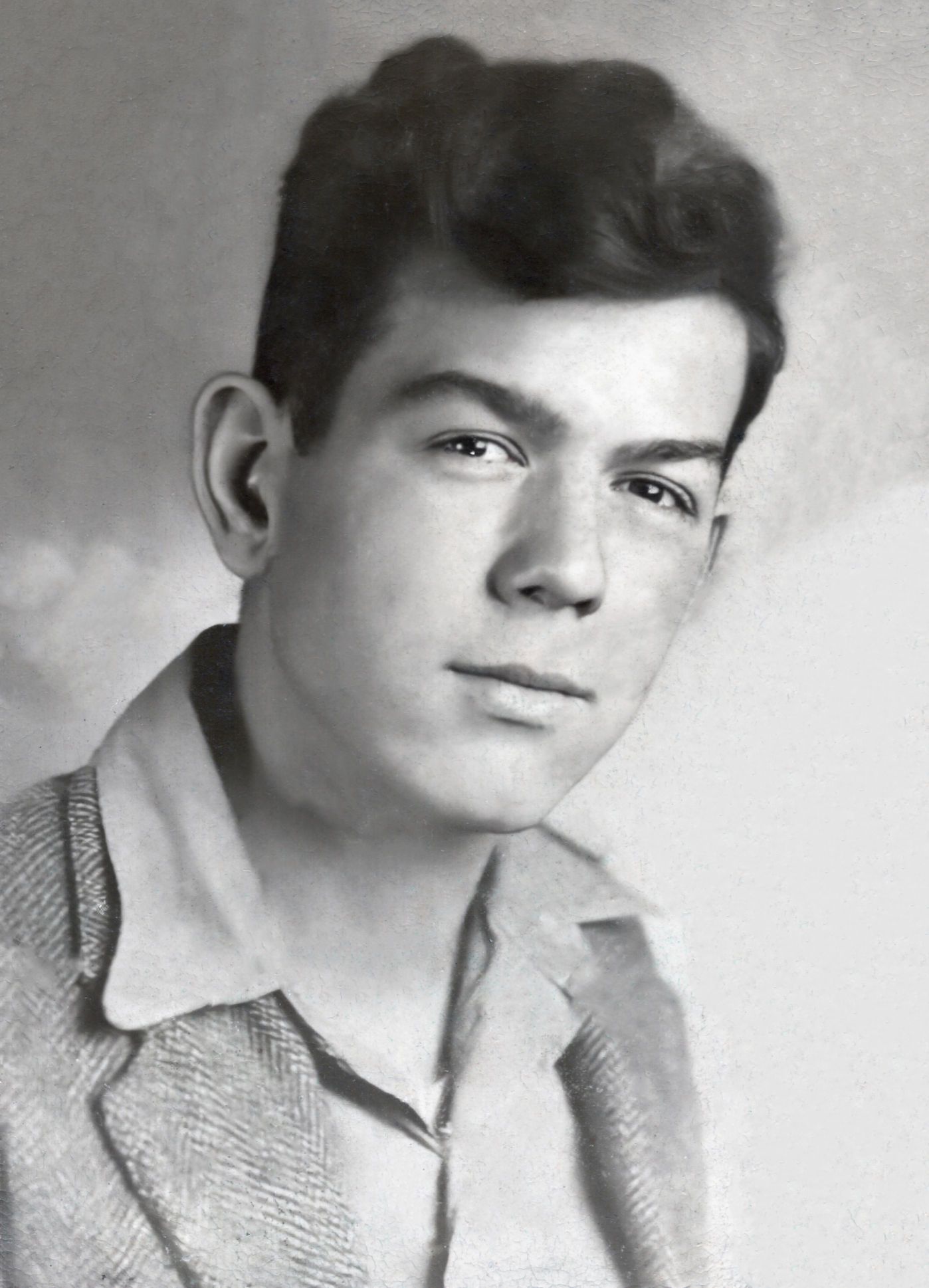 Vintage black and white portrait of a young man with dark hair wearing a collared jacket, formal studio photo.