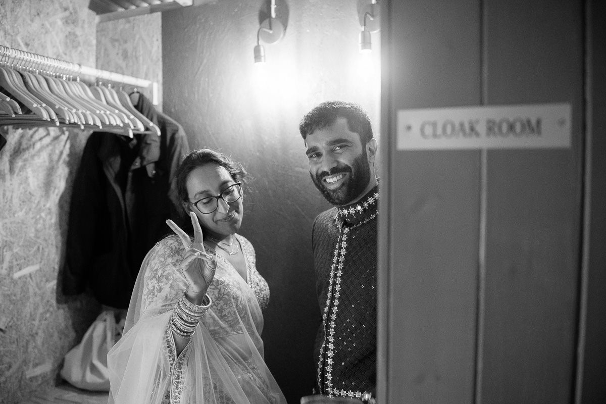A candid black and white moment of laughter and joy backstage near a cloak room sign.