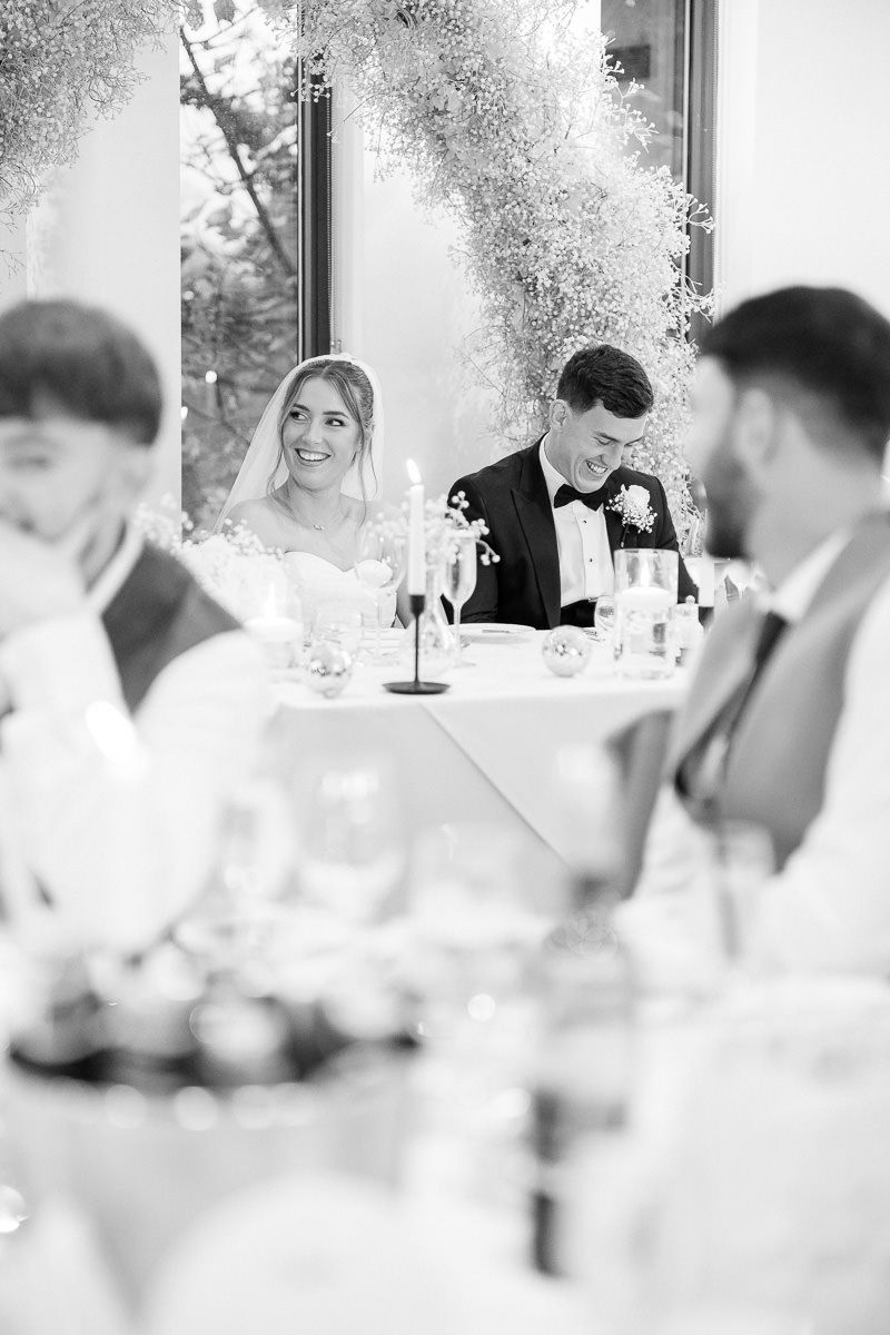 Wedding reception guests seated at elegant tables with white decor and floral arrangements at West Tower venue.