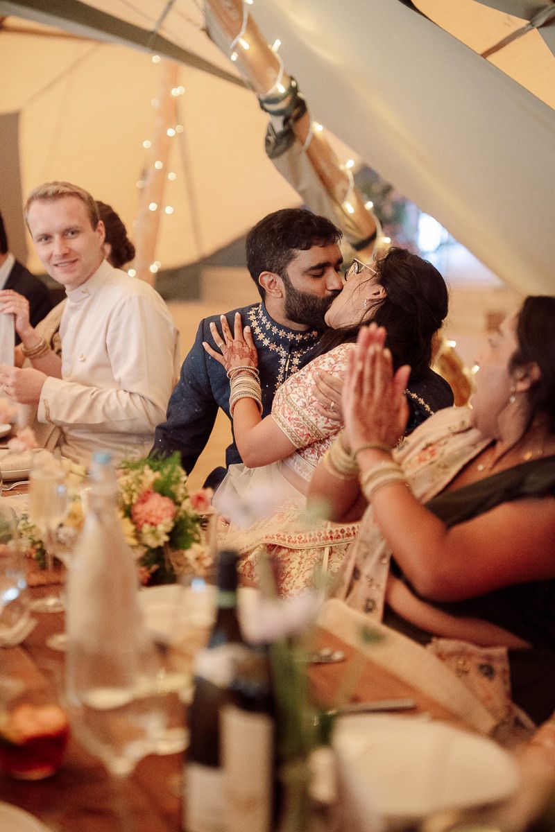 Festive wedding reception dinner under string lights with guests celebrating at decorated tables.