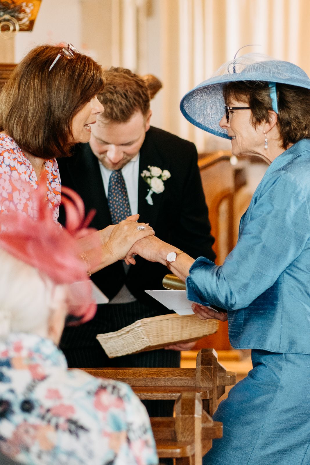 Guests in colorful attire share a joyful moment during a wedding ceremony at an elegant indoor venue.