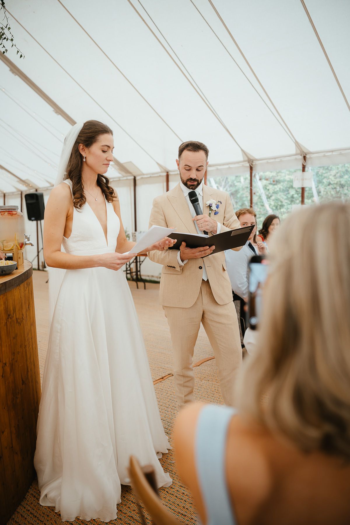 A elegant couple dancing together at their wedding reception under a white tent venue.