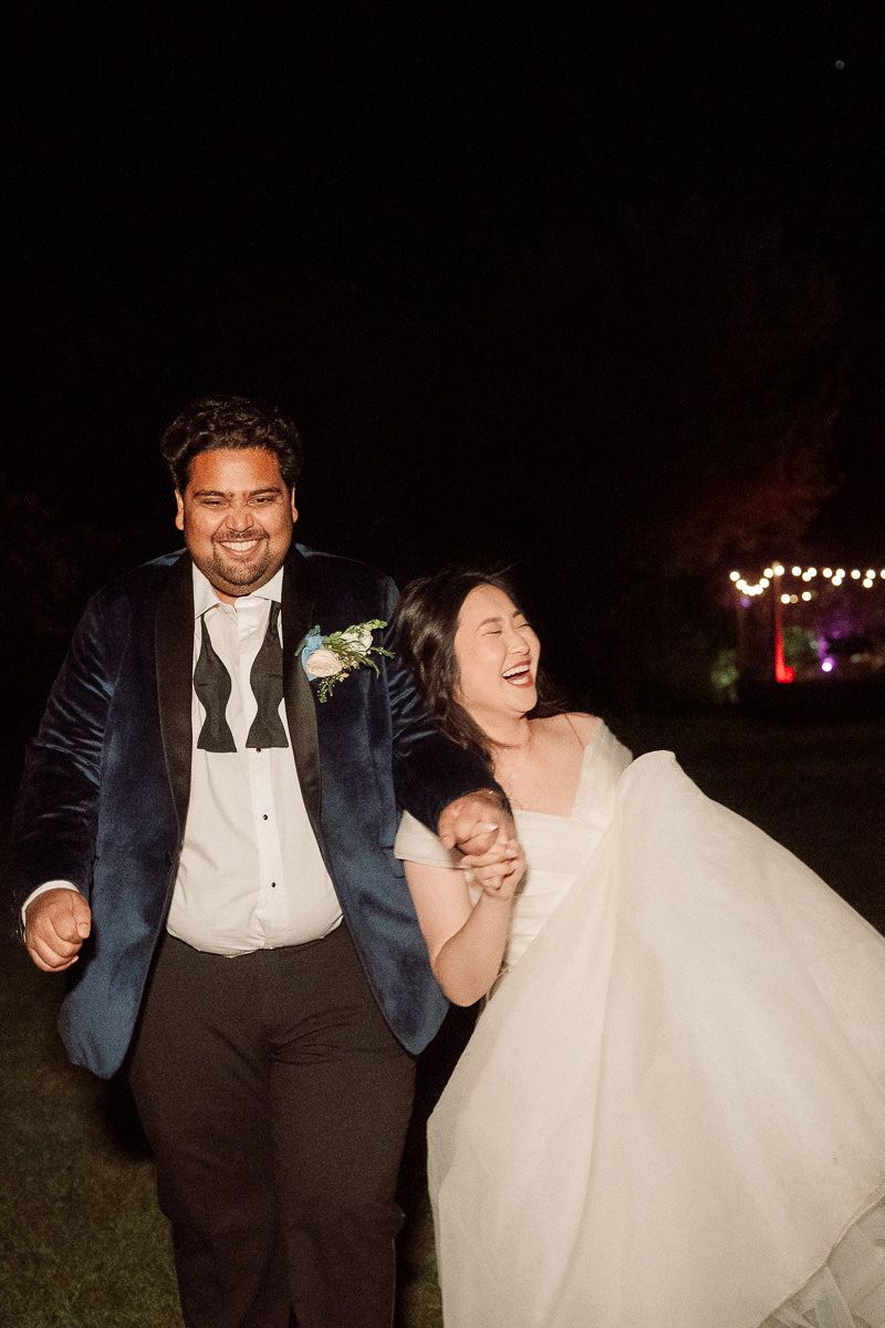 A couple shares joyful moments together during an outdoor nighttime wedding celebration at the Old Mill at Aldermaston