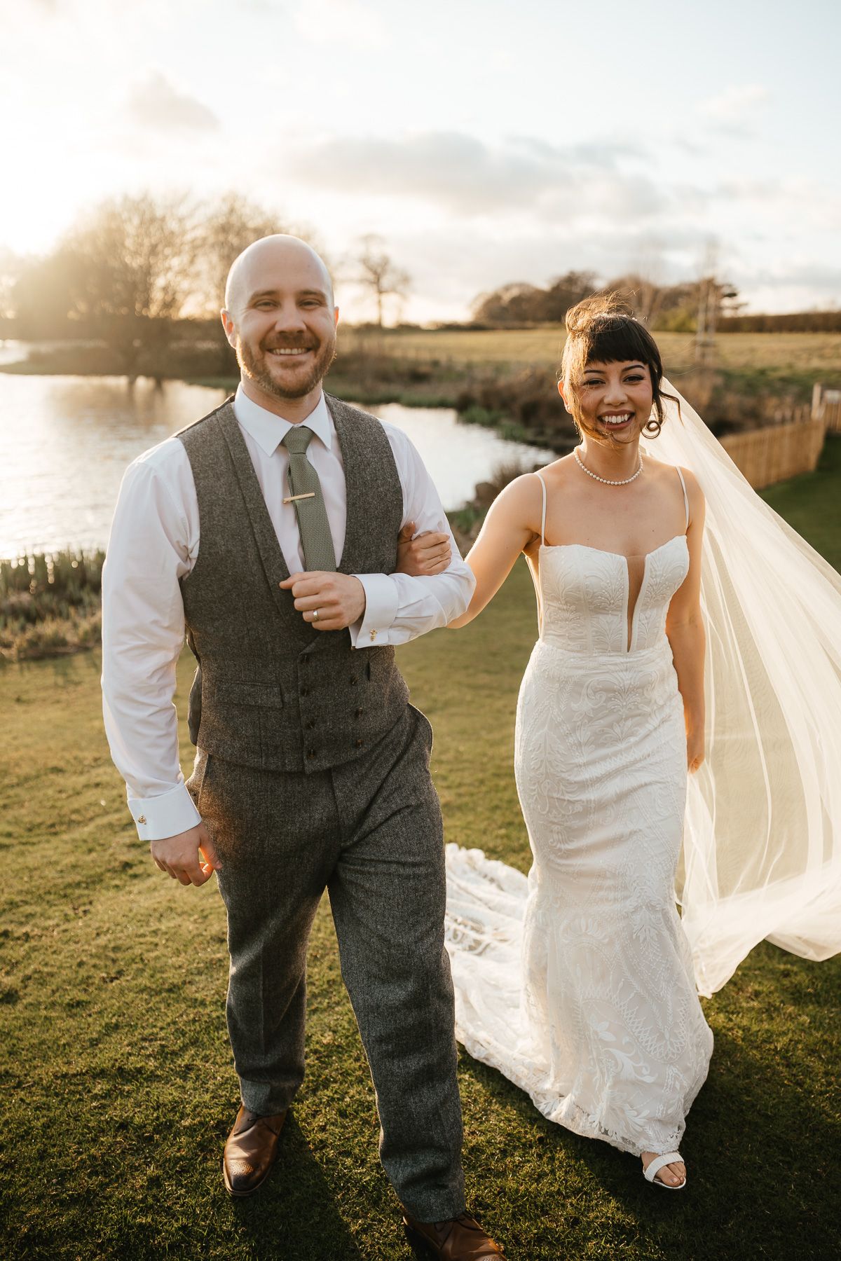 Candid outdoor wedding photos capture joyful moments between newlyweds against a sunset landscape.