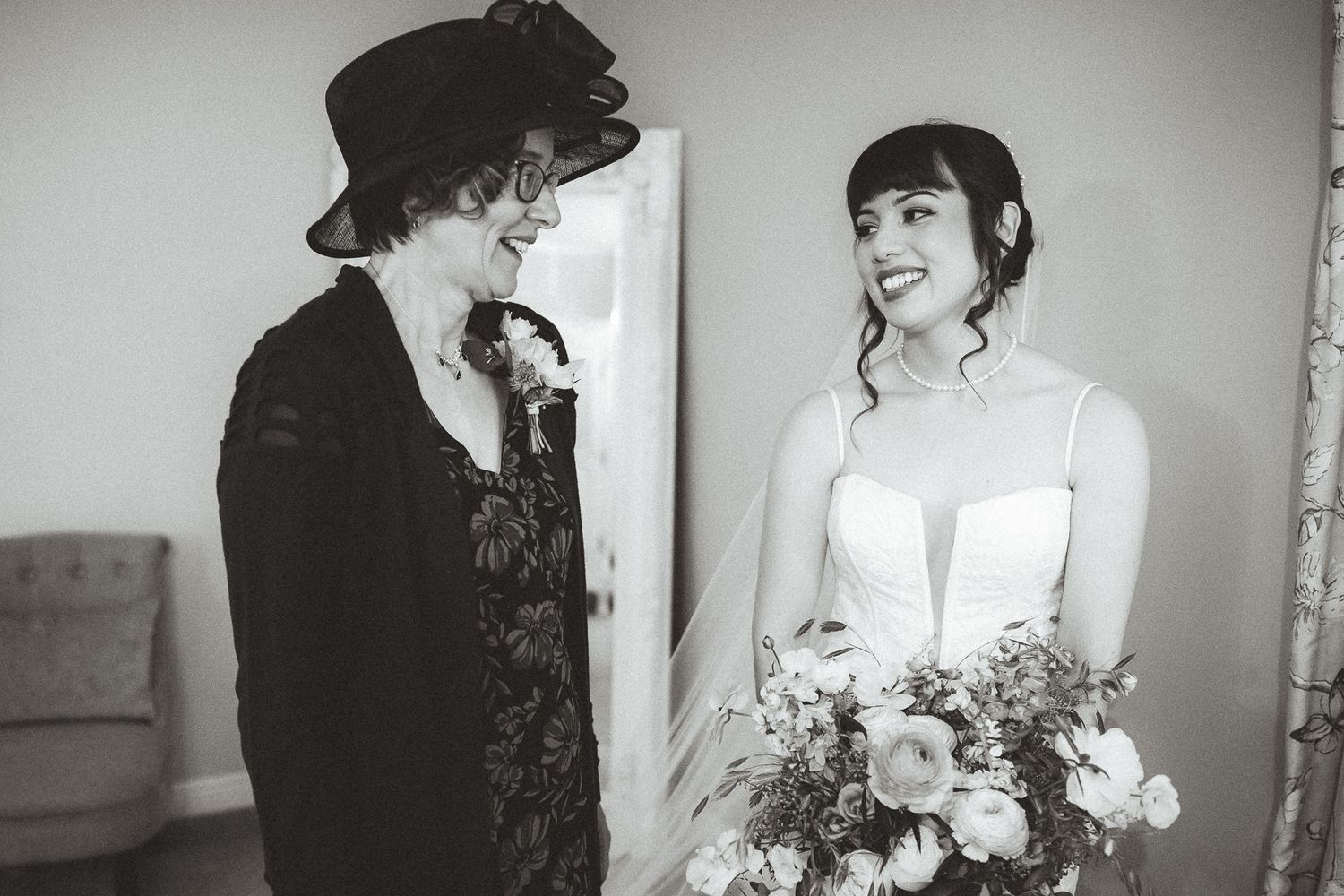 A heartwarming black and white moment between two people on a wedding day as they admire a floral bouquet.