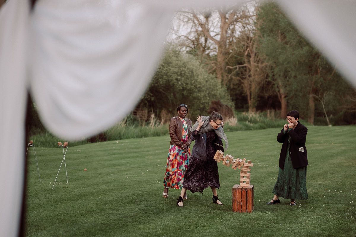 A series of outdoor wedding ceremony photos showing guests gathered on a grassy lawn with white fabric decorations.