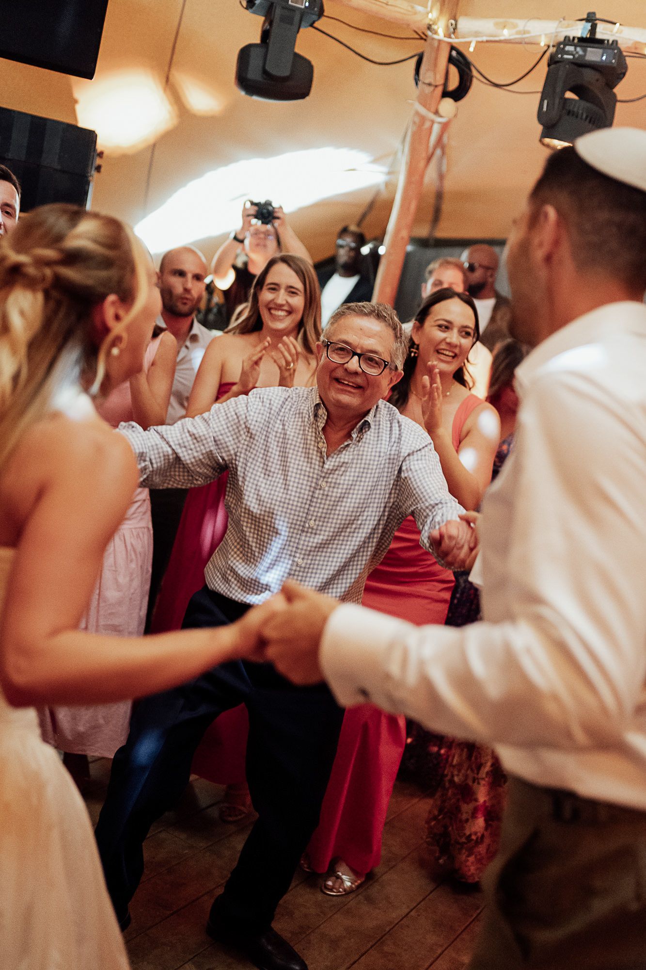 Joyful wedding guests dancing together at a lively indoor reception celebration.