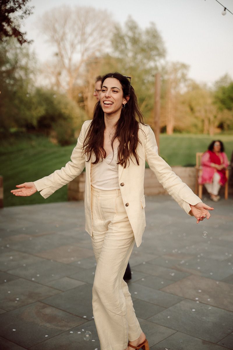 A sequence of candid shots shows a person in a cream-colored suit dancing joyfully outdoors at sunset at the Old Mill at Aldermaston wedding