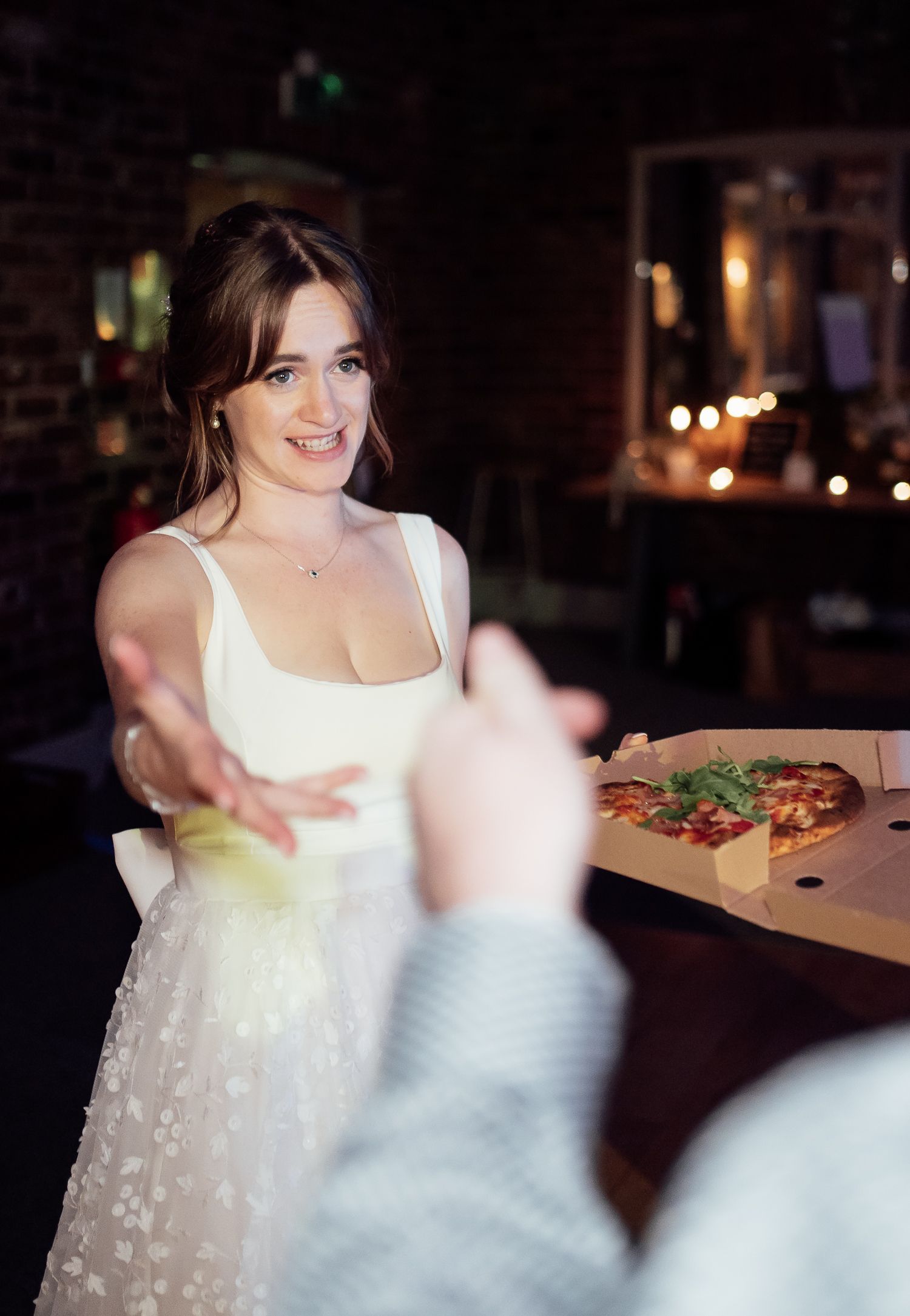 A person in a white flowy dress sits at a table during an intimate candlelit gathering, creating a dreamy atmosphere.