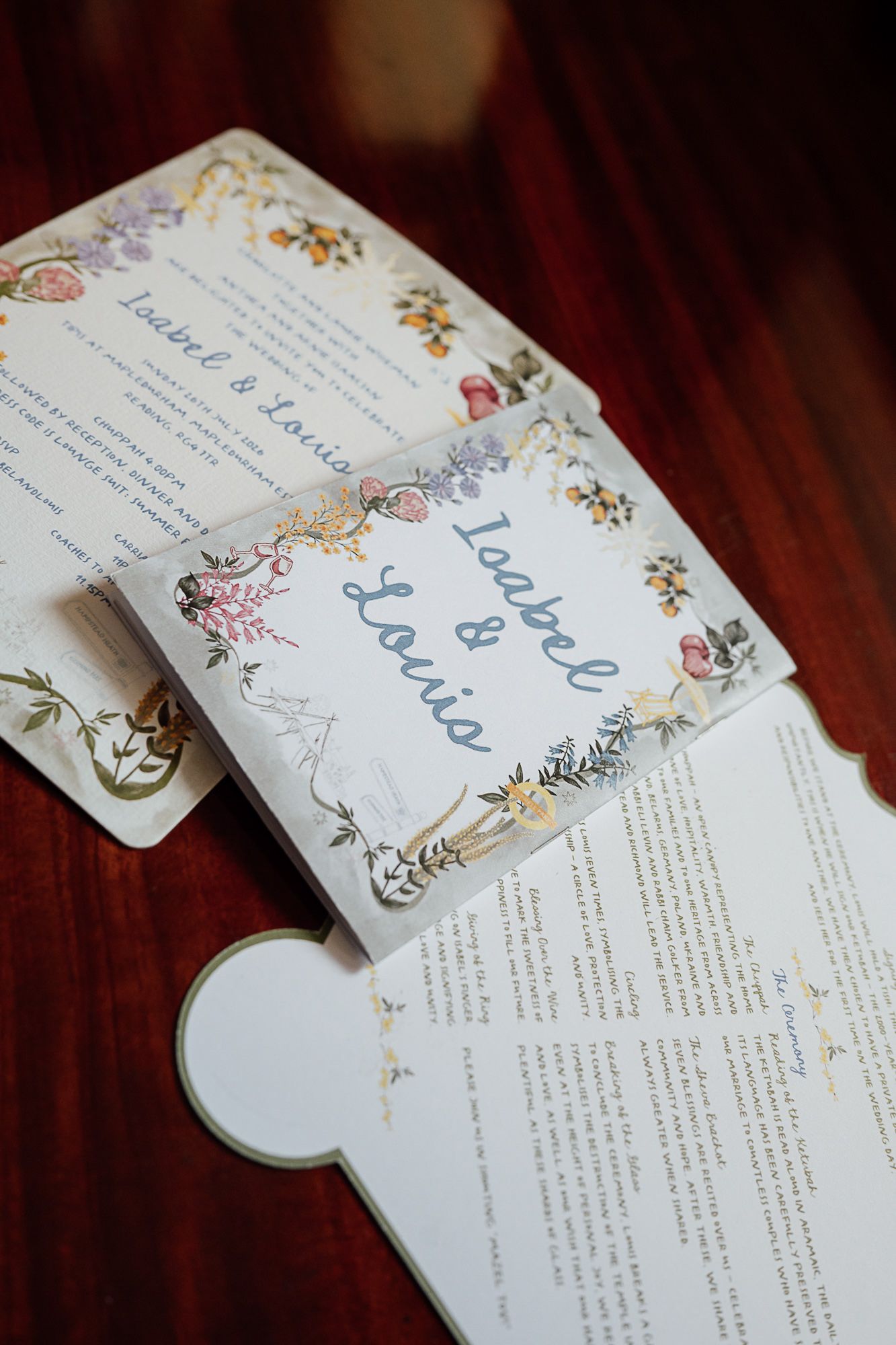 Elegant floral wedding invitation suite for Isabel and Louis displayed on a wooden table.