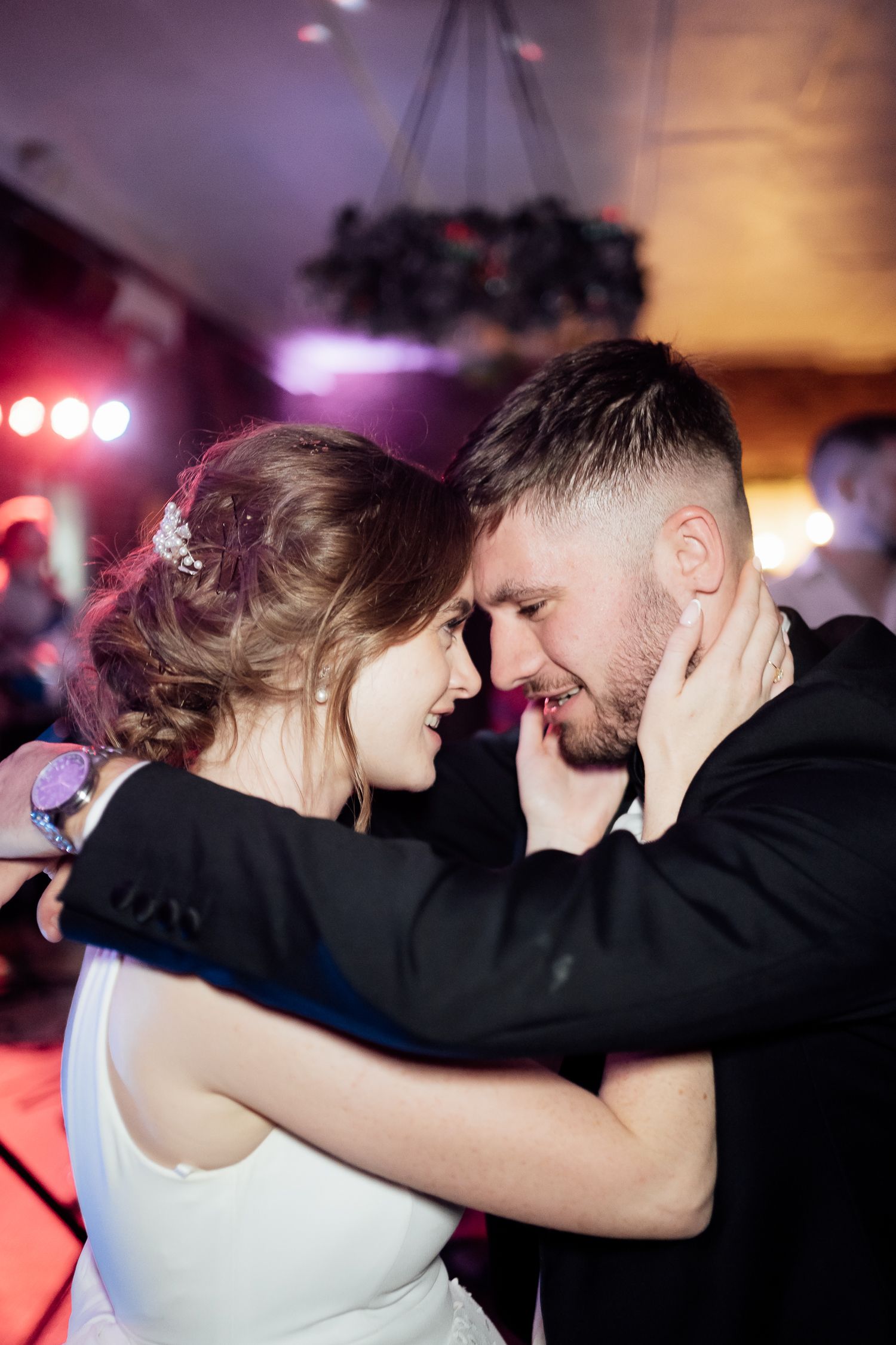 A romantic couple shares an intimate moment on the dance floor during what appears to be a wedding reception.