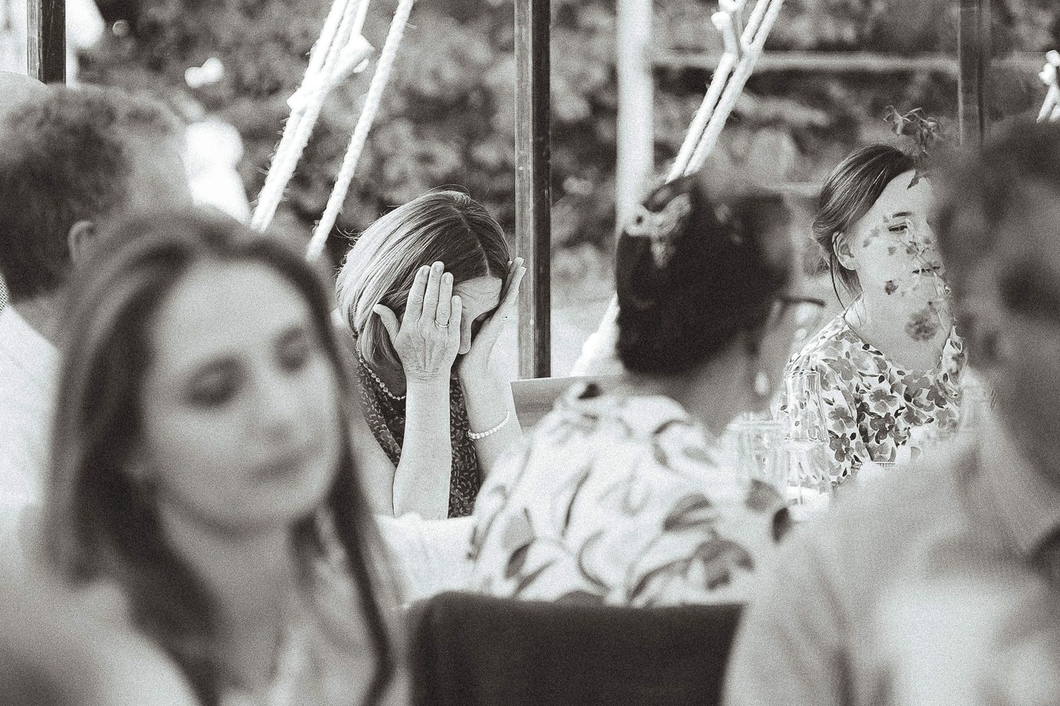 A candid black and white wedding reception moment showing emotional reactions during speeches or toasts.