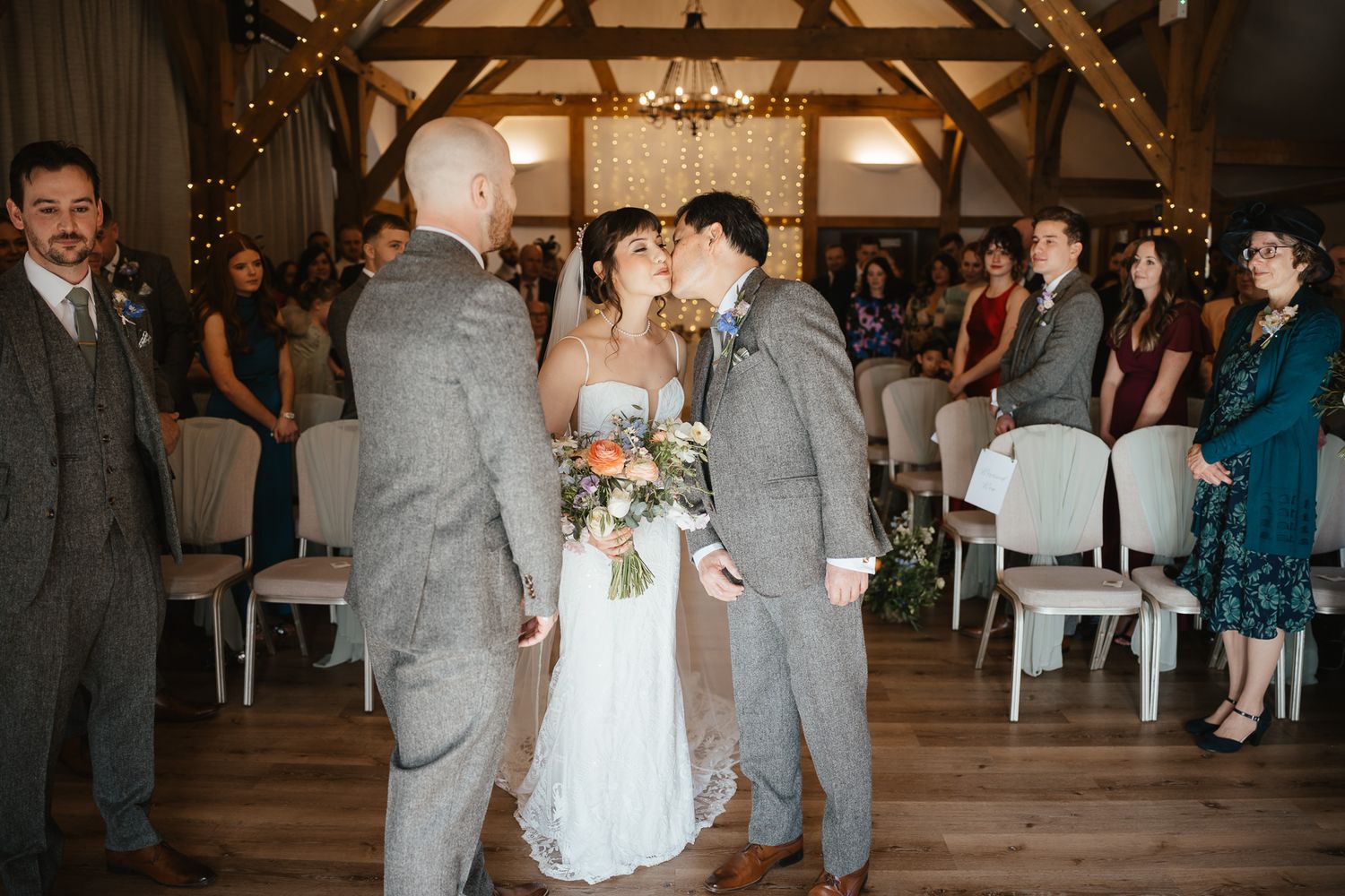 A couple shares their first dance during a reception in a beautifully decorated rustic barn with twinkling lights.