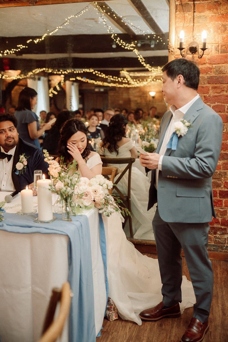 Wedding reception in a rustic brick venue with string lights and blue table runners.