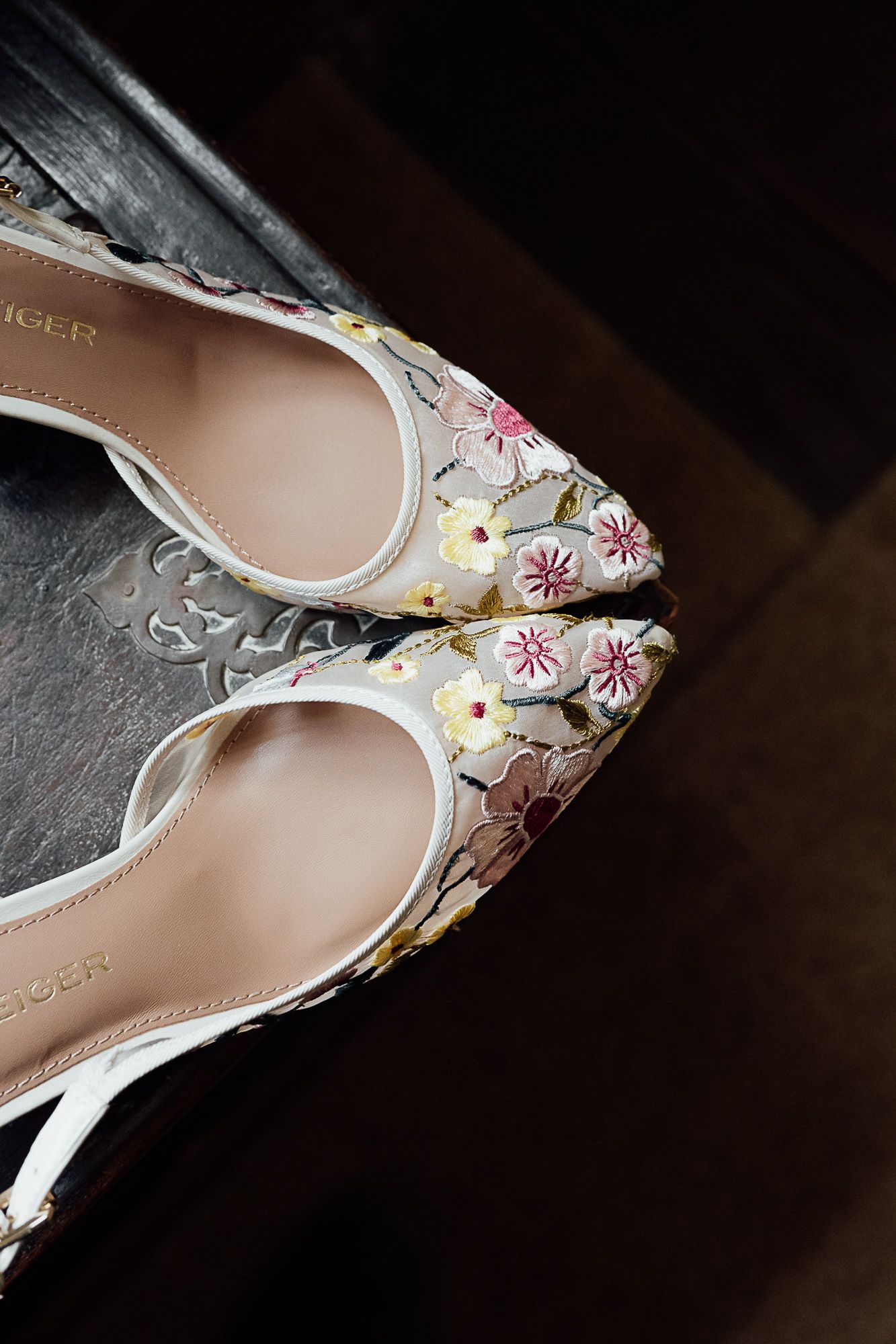 Floral embroidered pointed-toe heels by Tiger, featuring pink and yellow flowers on white fabric.