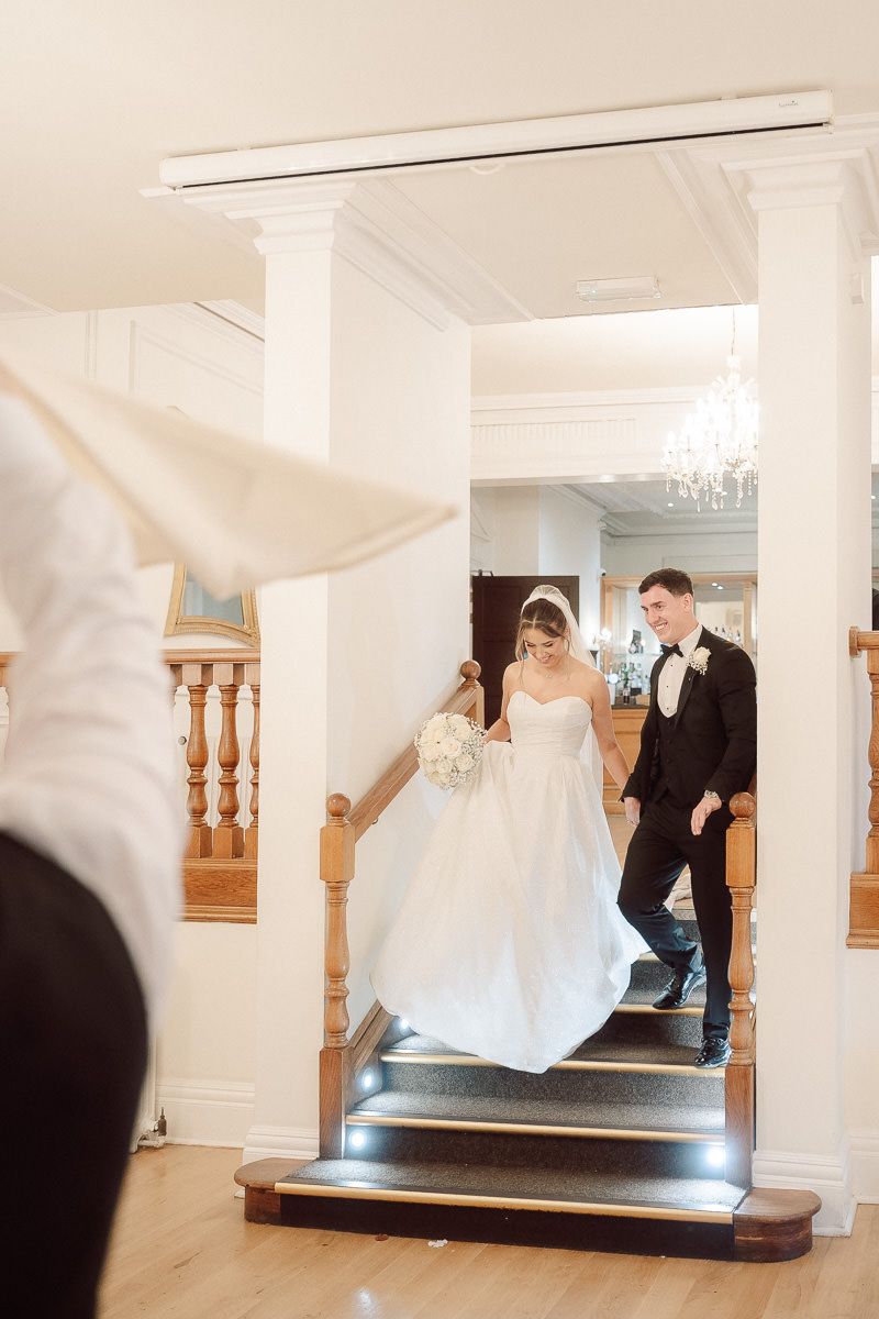 Motion sequence showing a couple descending a grand staircase in formal wedding attire.