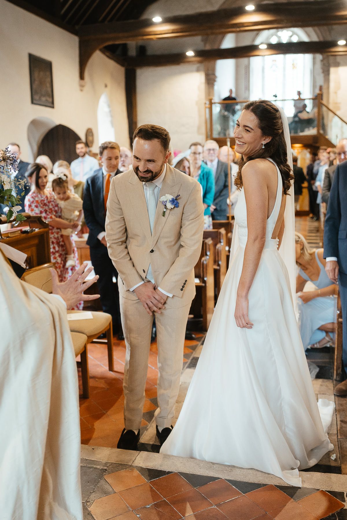 A joyous wedding ceremony takes place inside a rustic church with terracotta floors and exposed wooden beams.