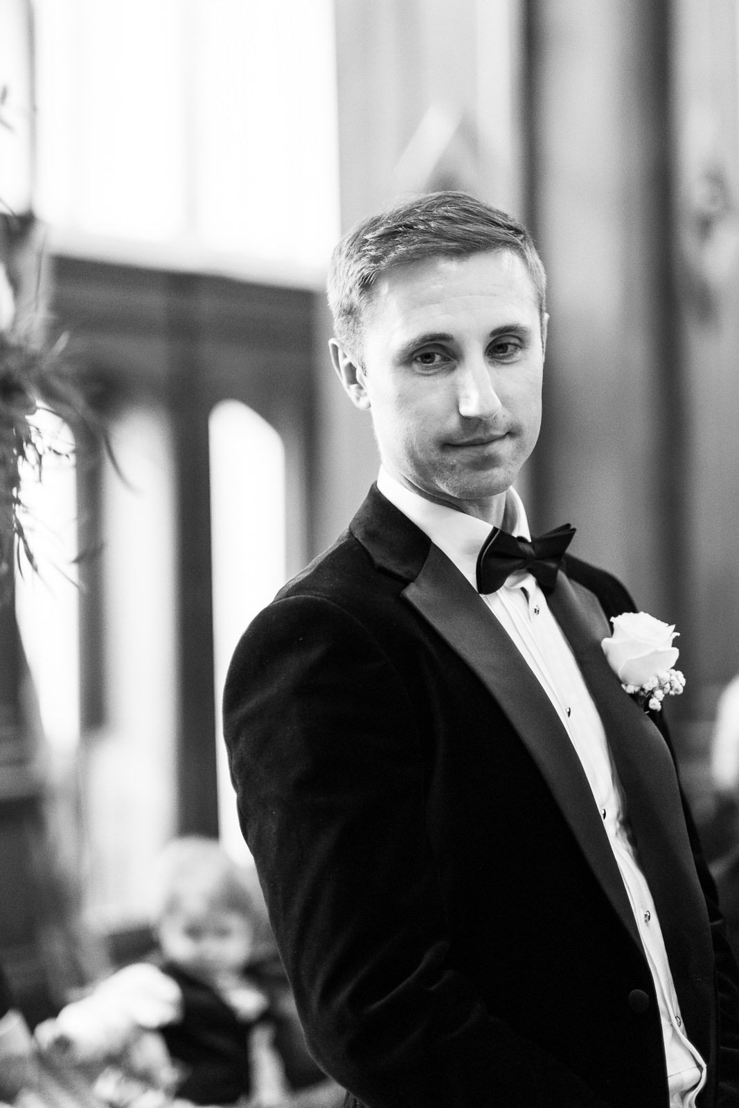 Black and white wedding photo series of groom in tuxedo showing different expressions during formal portraits.