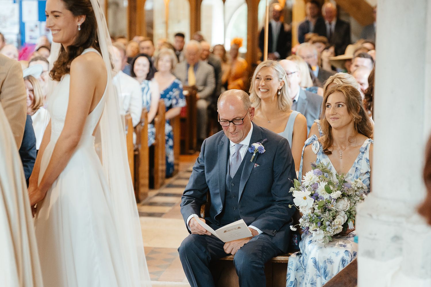 An emotional moment captured during a traditional wedding ceremony in a sunlit church with decorated wooden pews.