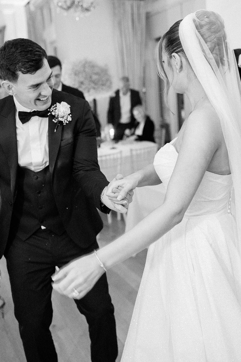 A black and white photo series showing joyful moments between a bride and groom during their wedding celebration.