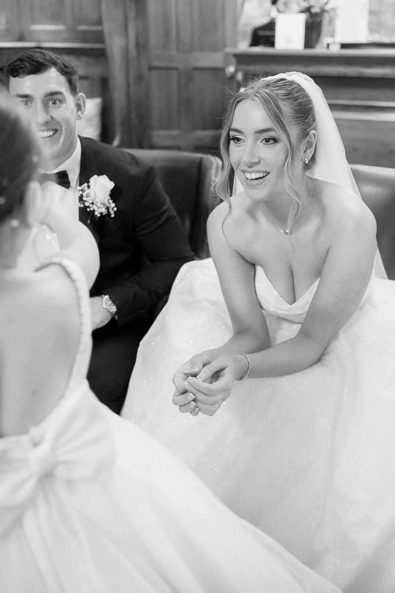 Black and white wedding photo of newlyweds sitting together and smiling during their ceremony.