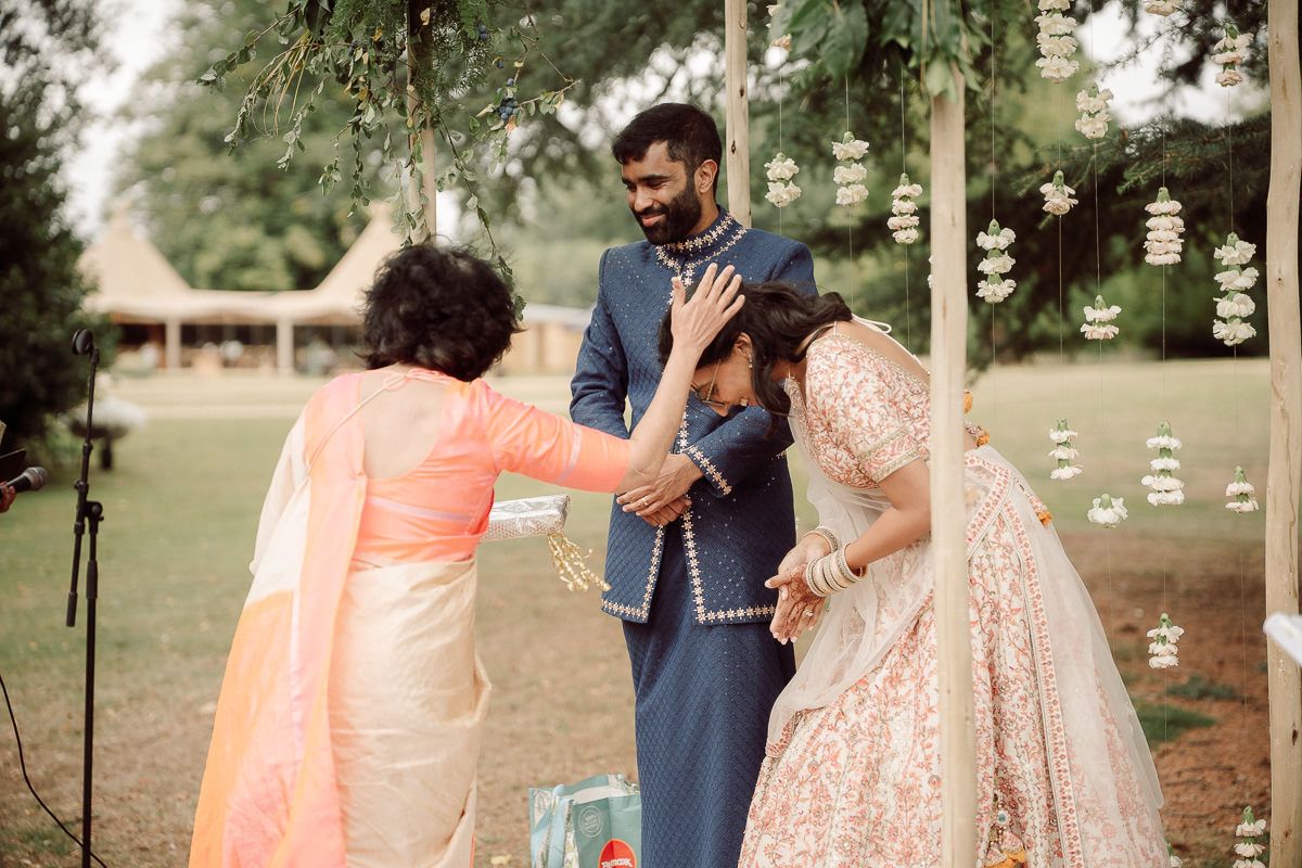 Couple in navy and peach wedding outfits embracing during an outdoor photoshoot.