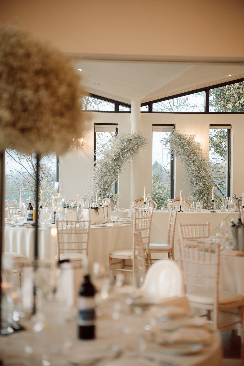 Wedding reception venue with white chiavari chairs and soft lighting creating an elegant atmosphere for celebration.