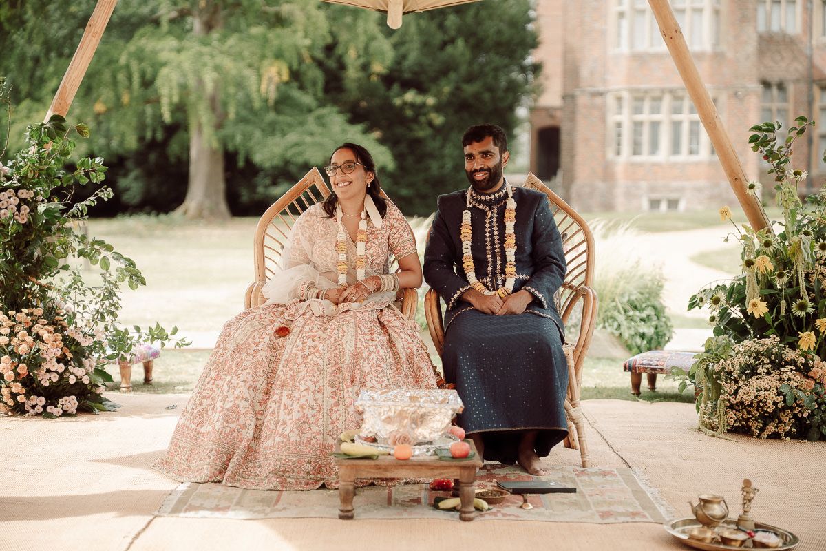 A couple sits together on a wooden swing in a lush garden setting during a romantic outdoor ceremony at mapledurham house wedding venue.
