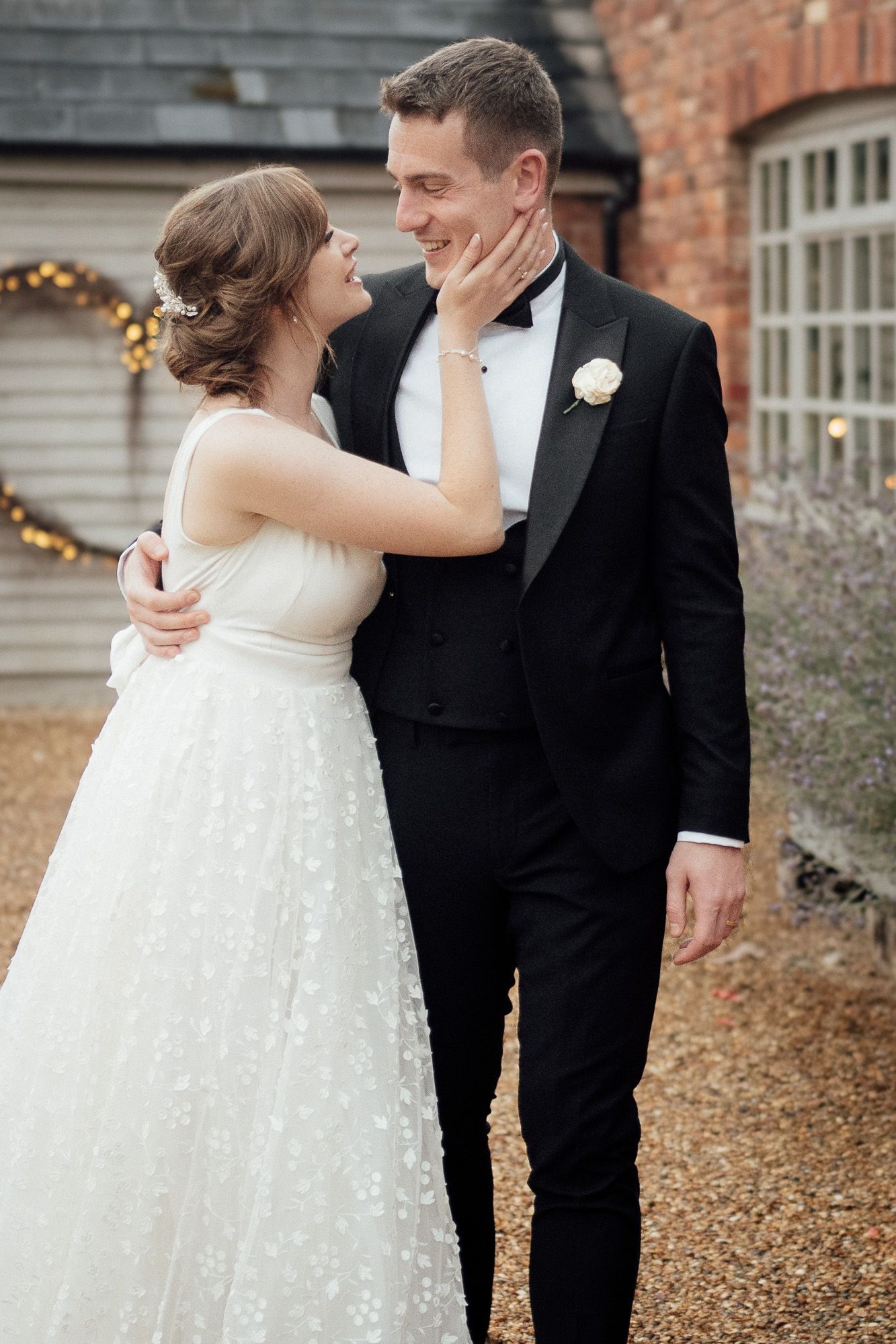 Wedding couple shares an intimate first look moment in autumn surrounded by brick buildings and falling leaves.