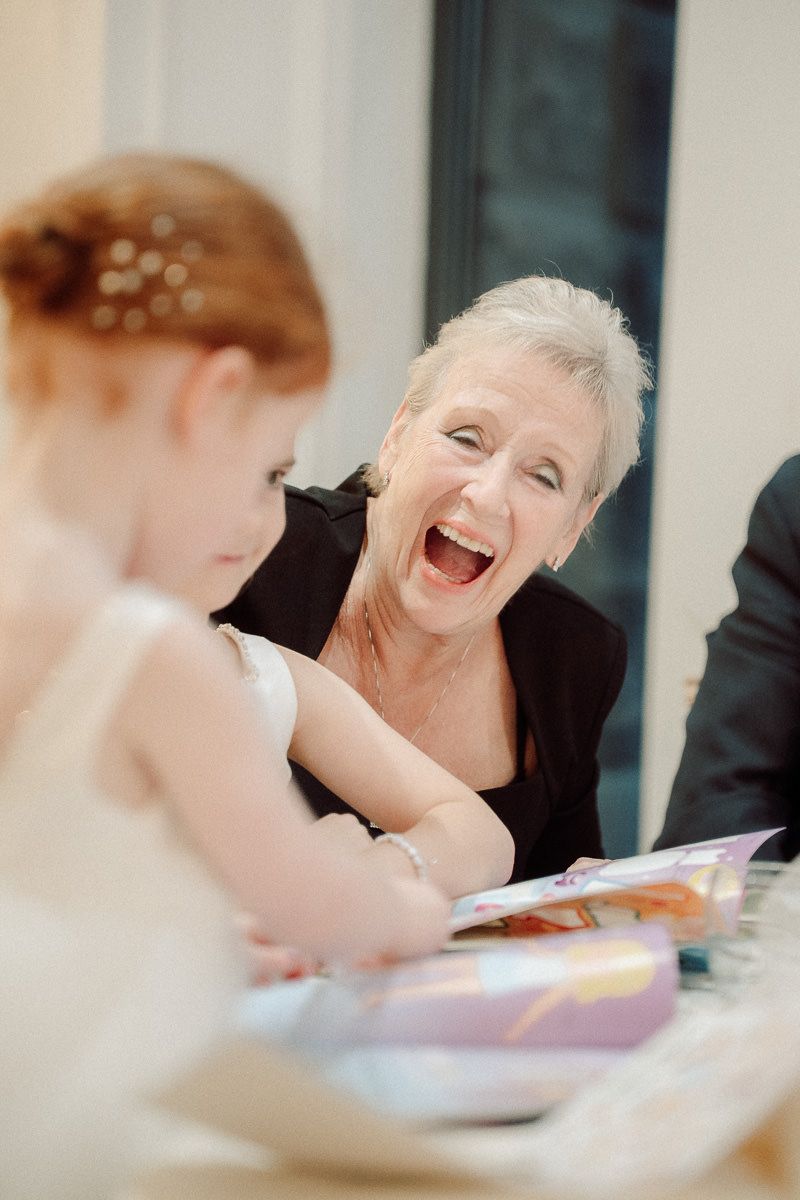 A sequence of photos showing a person laughing heartily at a dining table during what appears to be a formal event.