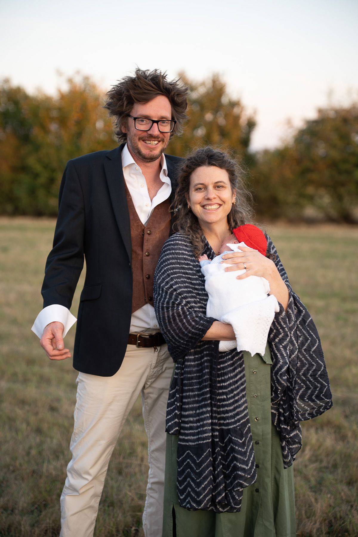 A couple shares tender moments together outdoors in a grassy field during a casual photo session.