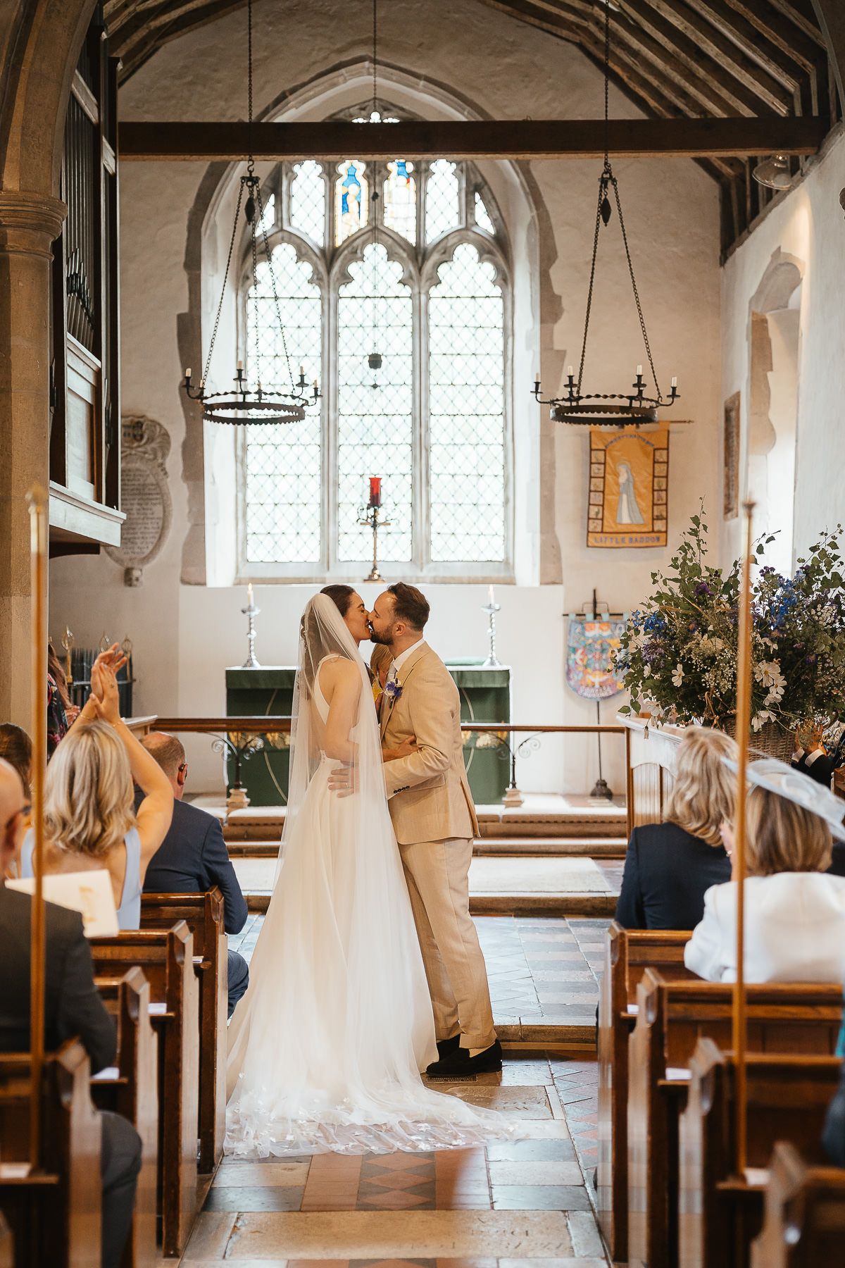 Wedding ceremony in a historic church with gothic windows, stone arches and rustic decor featuring candlelit chandeliers.