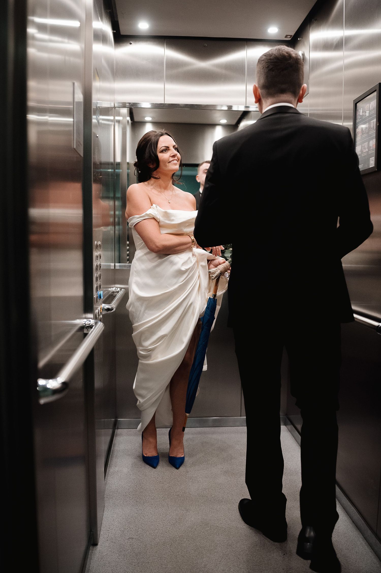 A sequence showing a person in white clothing scuffling with someone in a dark suit in an elevator hallway.