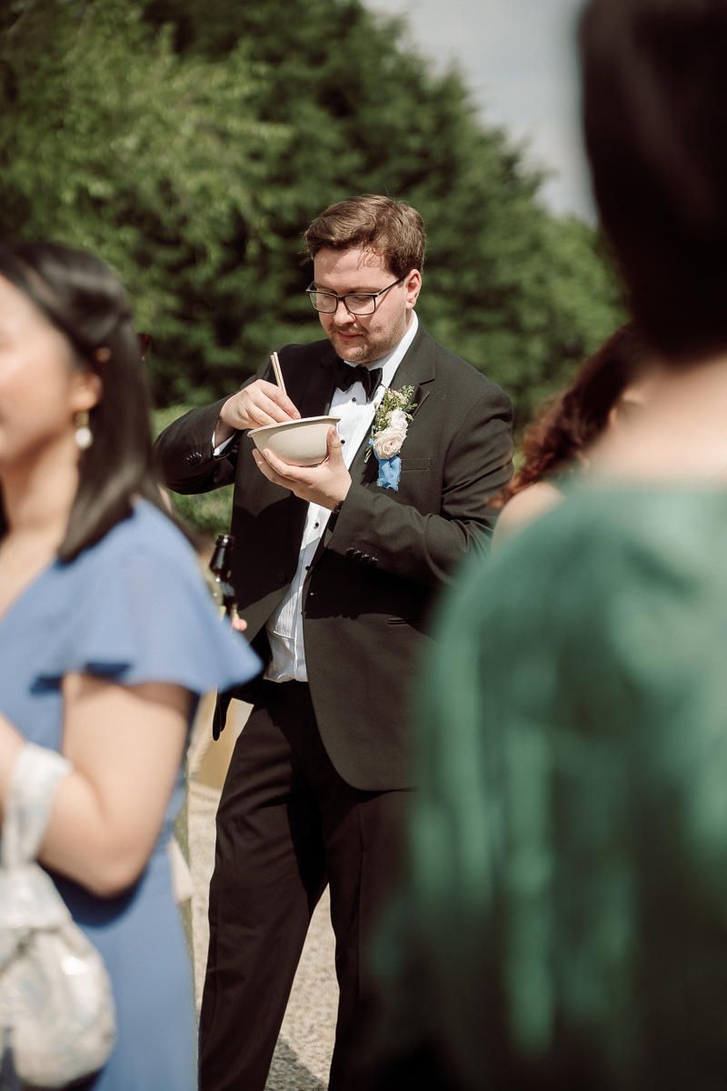 Emotional wedding moment captured as groom wipes tears during outdoor ceremony.