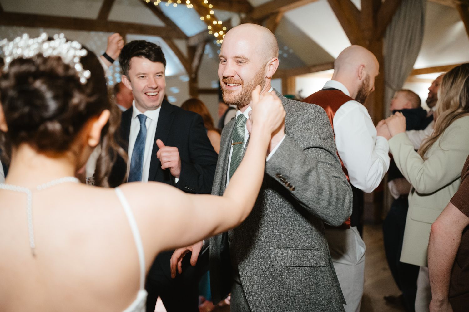 Wedding guests dancing and enjoying themselves on the dance floor at a reception celebration in an indoor venue.