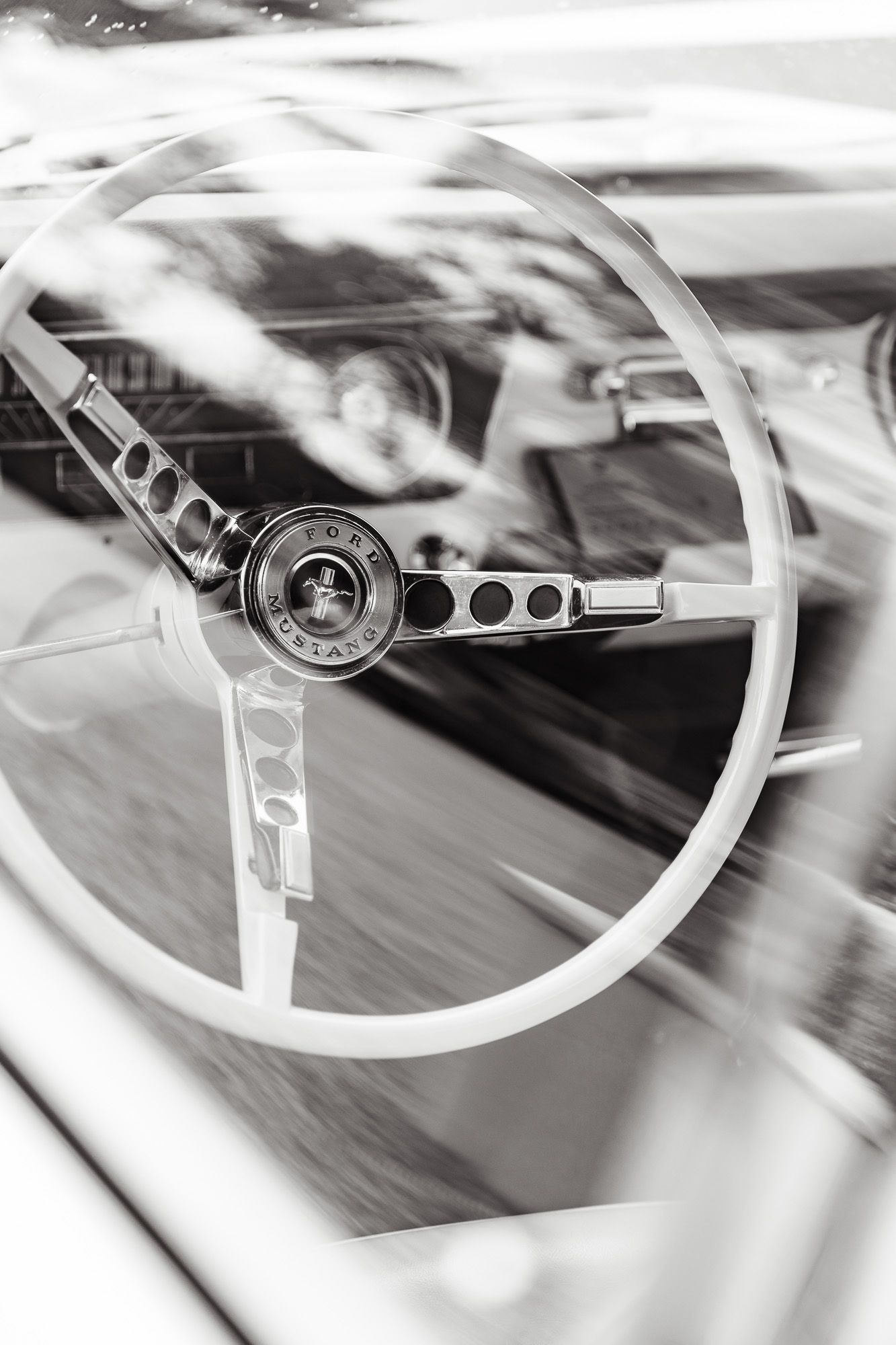 Classic vintage Mustang steering wheel detail in dramatic black and white photography.