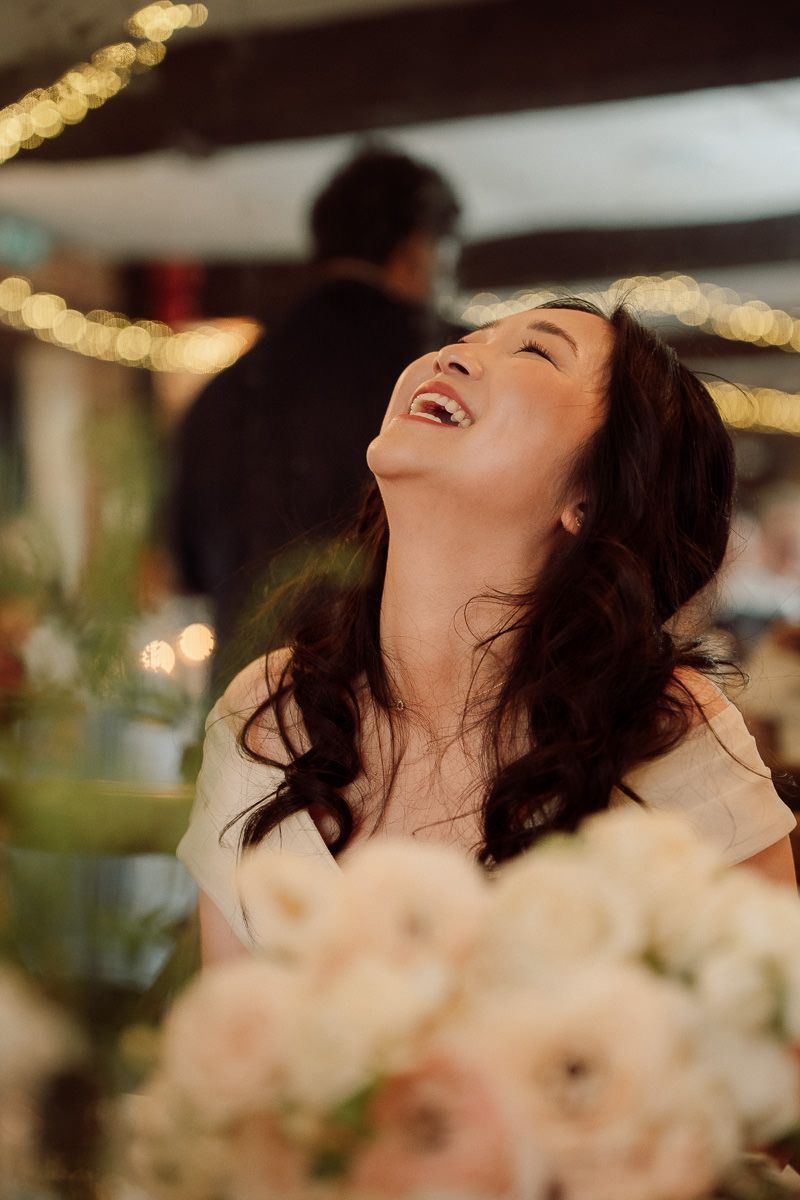 A person throws their head back in joyful laughter with bokeh lights glowing in the background.