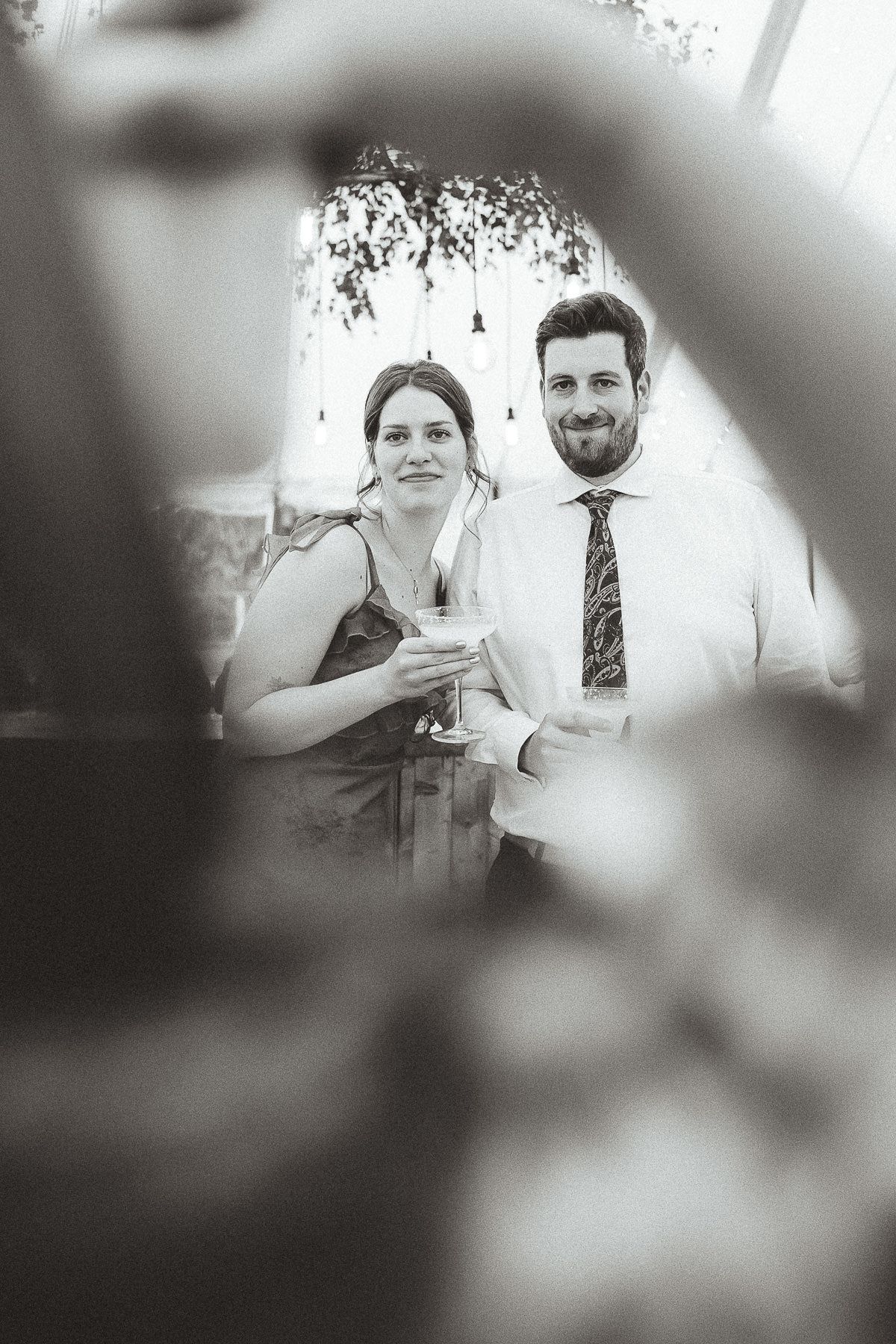 Wedding reception guests enjoying celebratory drinks at an outdoor event with blurred background.