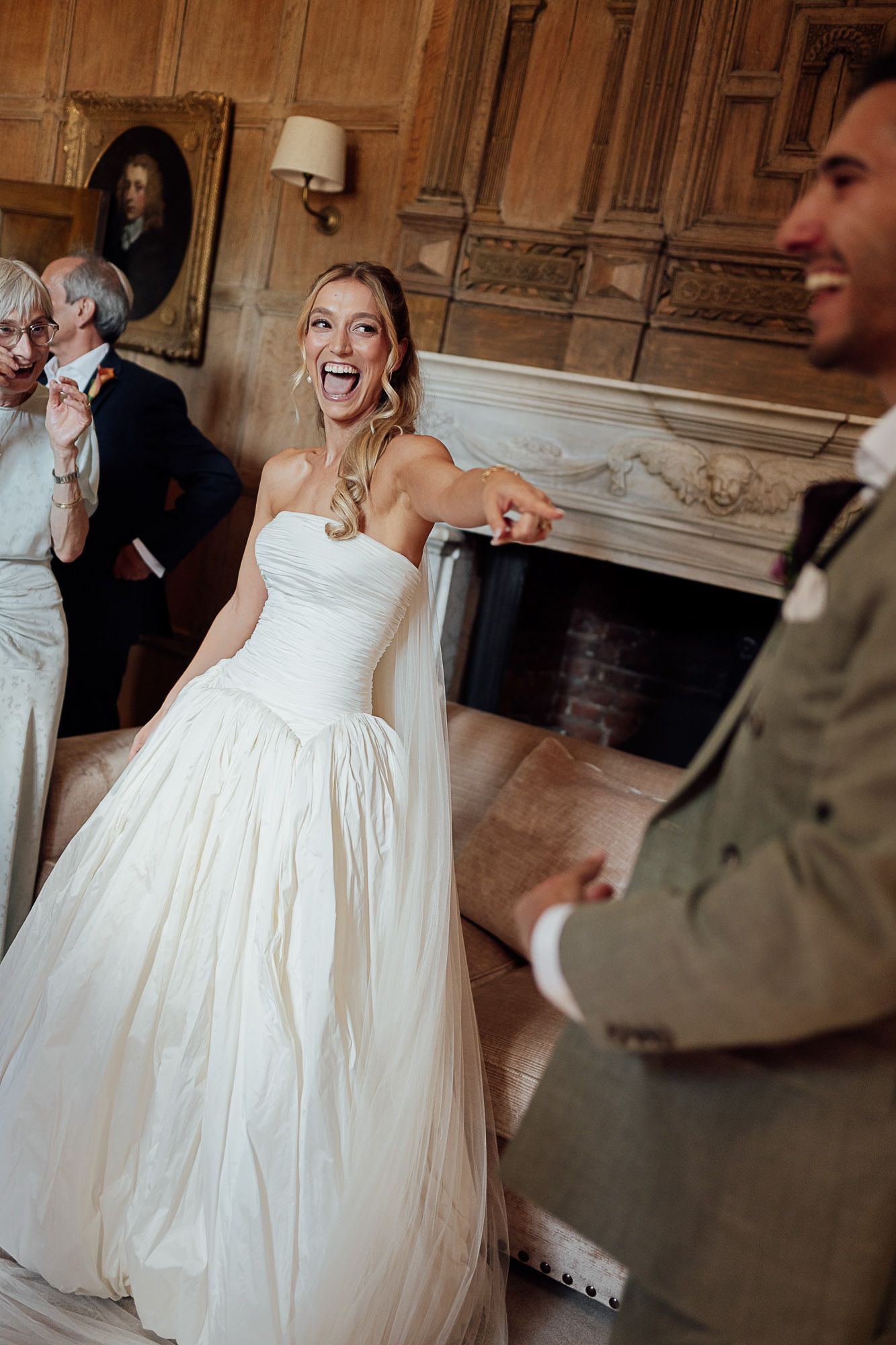 Excited bride in strapless white ballgown laughing with groom at elegant wedding venue.