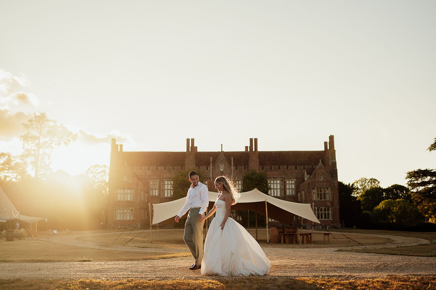 Bride and groom dancing at golden hour sunset outside a historic brick manor house wedding venue.