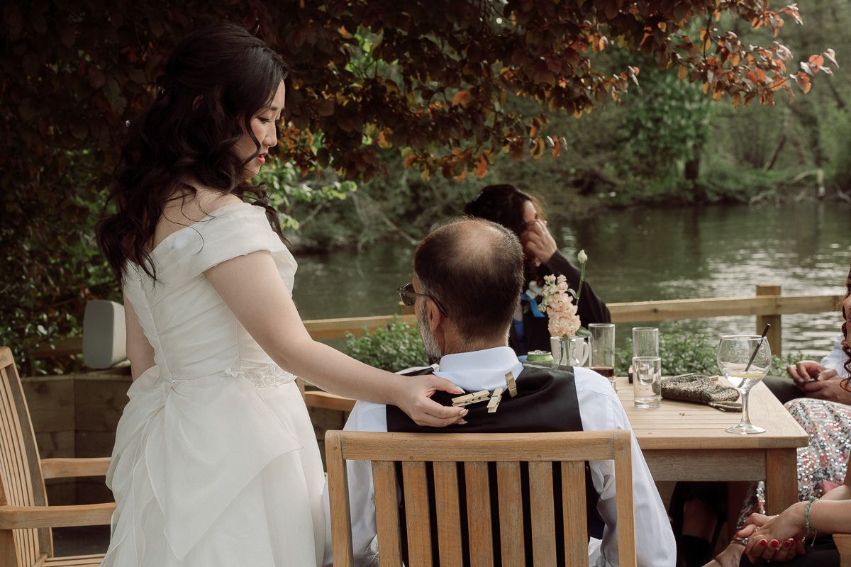 Couple sitting together on wooden bench by tranquil lake surrounded by autumn foliage.