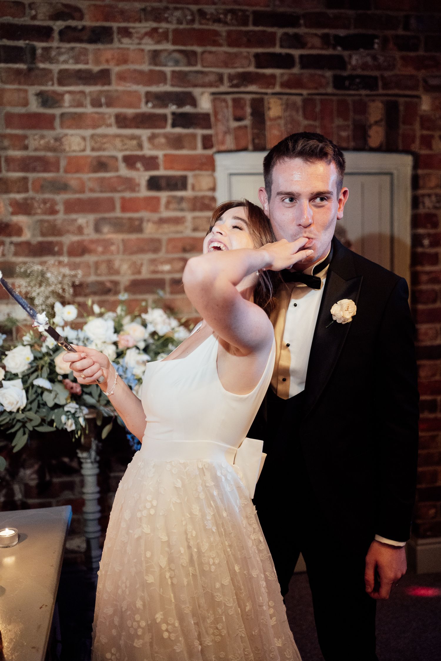 A couple dances in an elegant twirl, with the bride wearing a sparkling white dress against exposed brick walls.