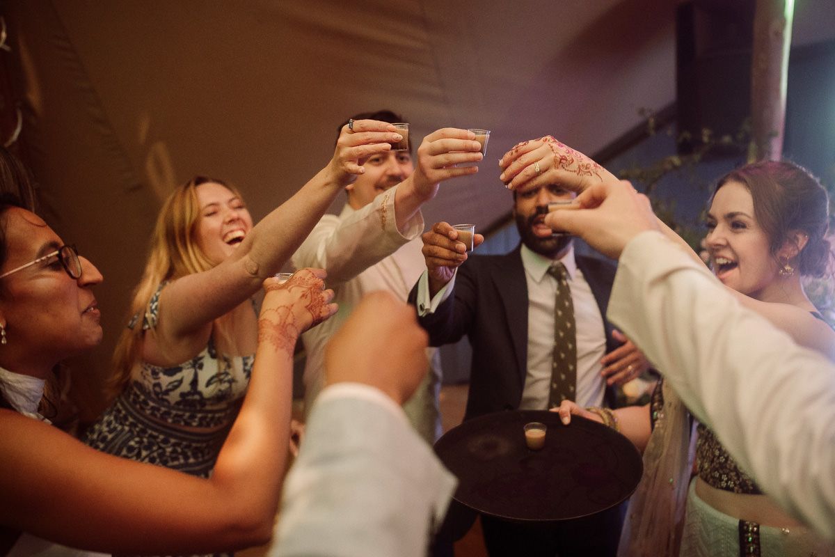 Wedding guests raising glasses in a celebratory toast during reception party at mapledurham house wedding venue.