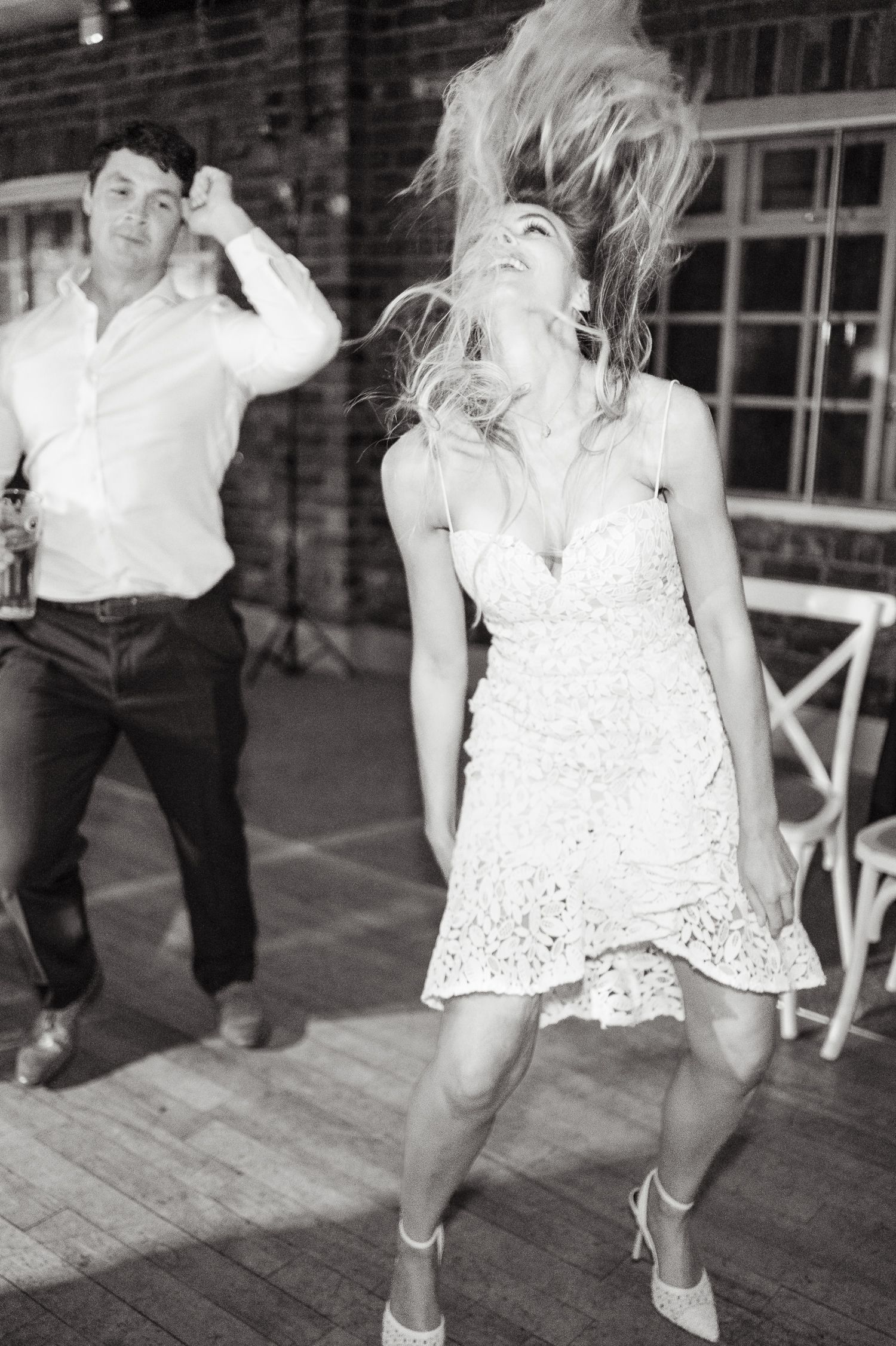 Black and white photo of dancers having fun on a wooden dance floor as woman flips her hair during an energetic dance move.