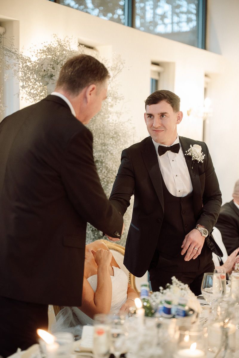 A sequence of five candid photos showing two men in formal attire interacting at an elegant dinner table setting.