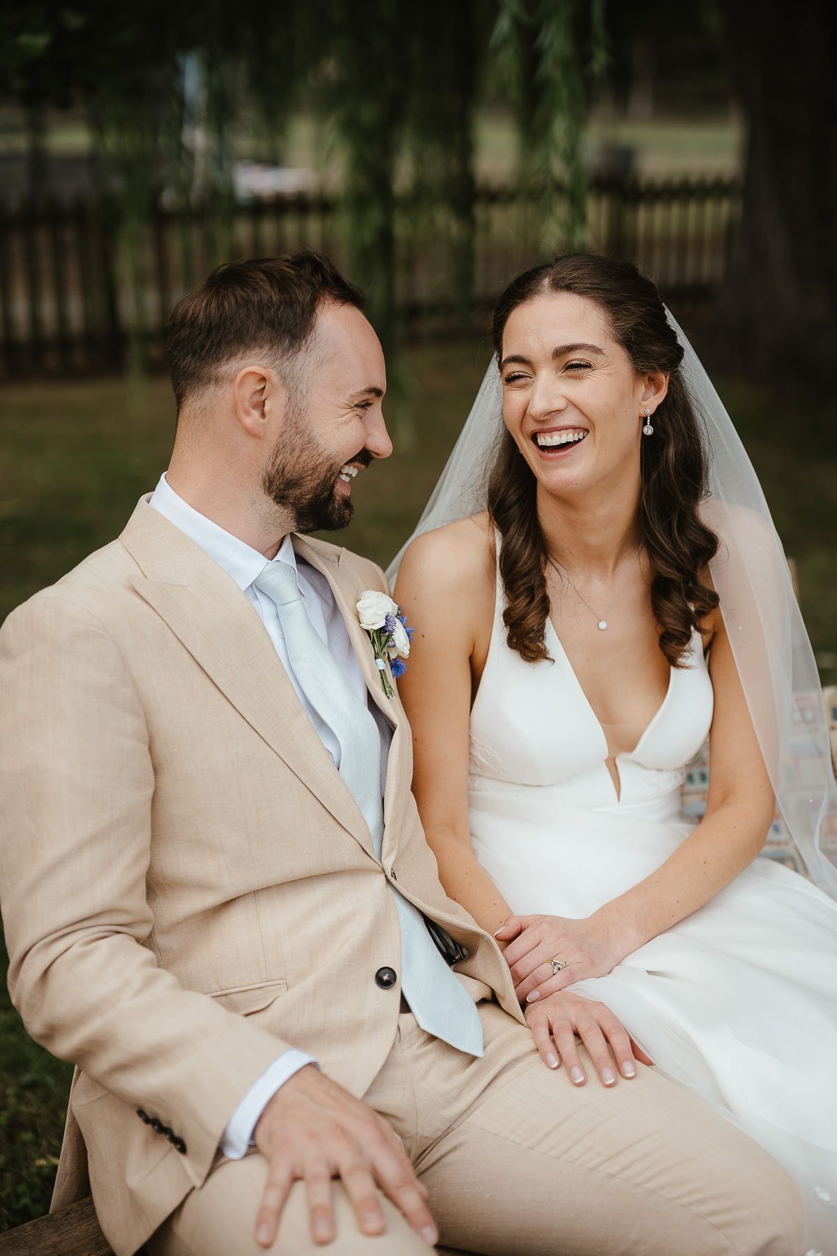 Joyful couple shares a candid moment of laughter during their outdoor wedding ceremony.