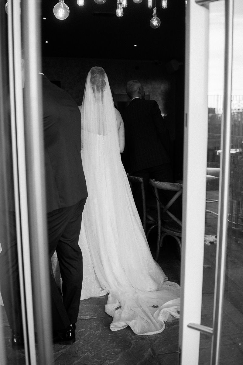 Black and white photo of wedding dresses hanging on display racks in a bridal boutique.
