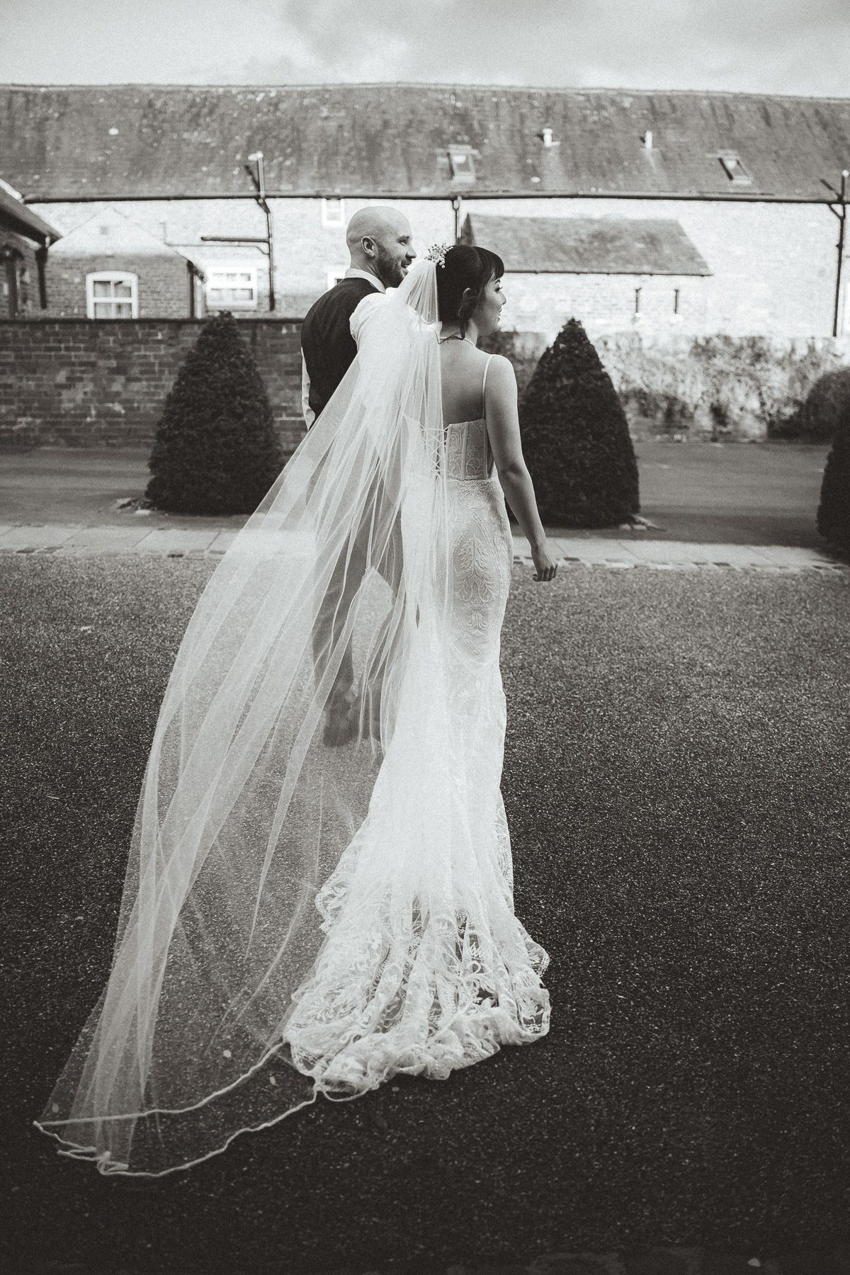 Ethereal black and white wedding photos showing the flowing movement of a bridal gown and veil across a grassy lawn.