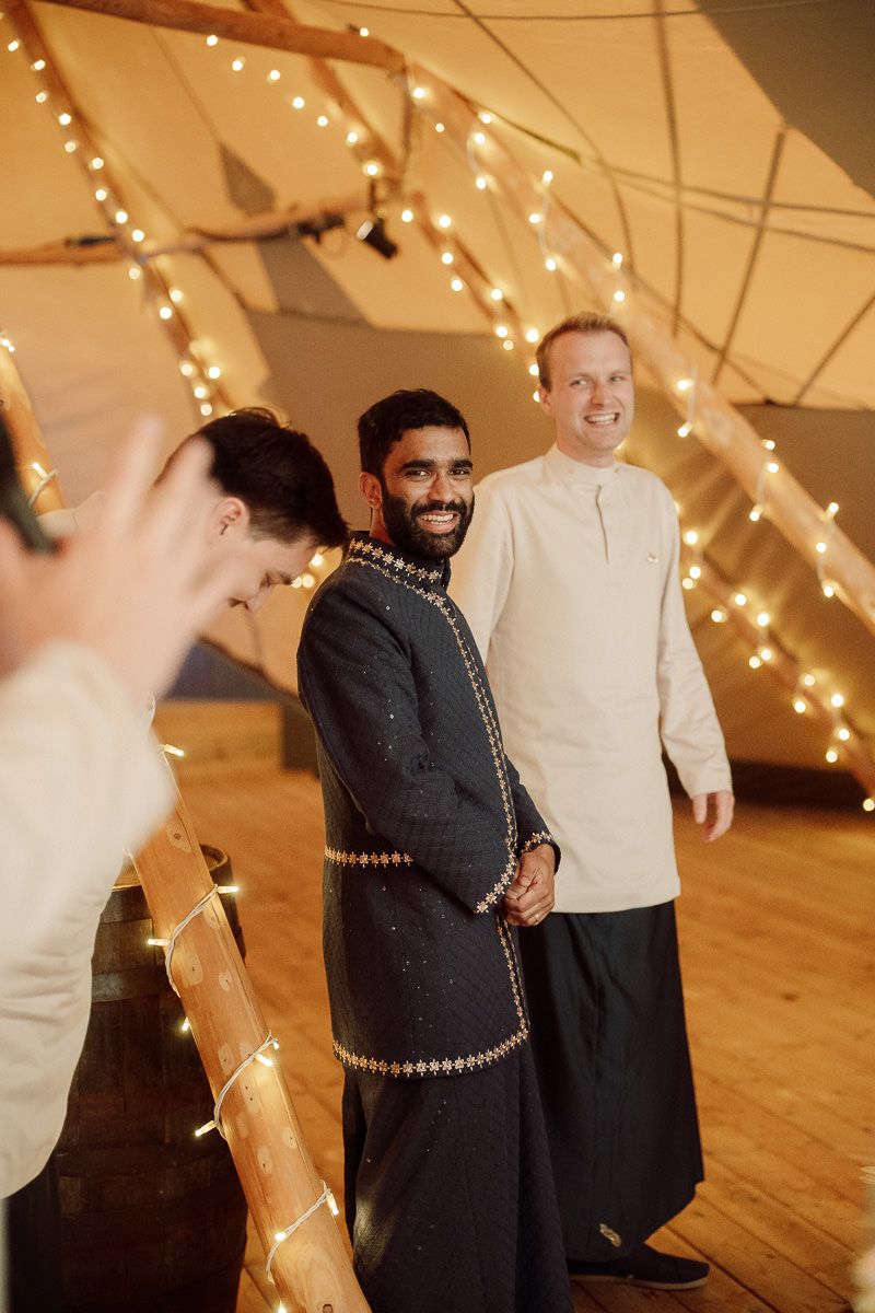 Wedding reception dance floor with string lights overhead as people dance and celebrate in warm lighting.