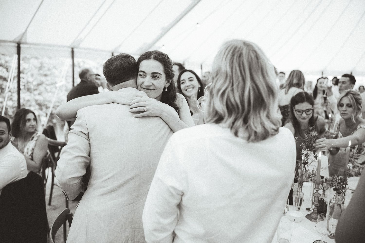 Group of wedding guests dance and embrace each other in a joyful celebration on a dance floor.